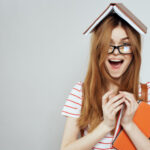 student smiling with a book on her head