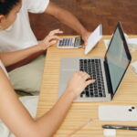 University student planning a weekly budget with calculator and notes.