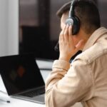 Man wearing his headphones in front of his laptop