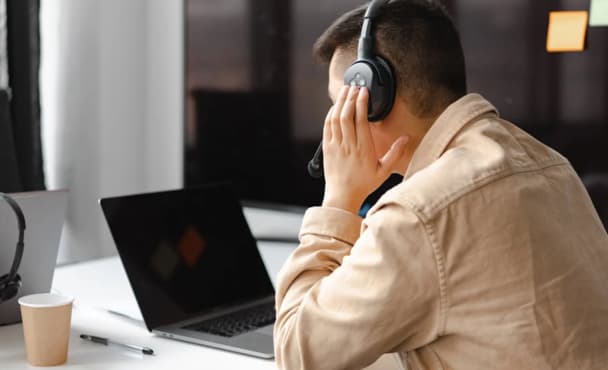 Man wearing his headphones in front of his laptop