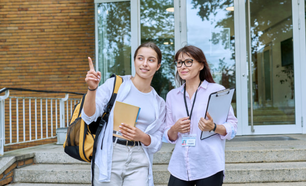 High-school student exploring a university open day with mother, walking down campus steps.