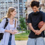 Young laughing teenage guy and girl talking together, urban background