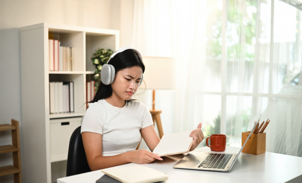 A teenage girl looks confused while studying online at home, struggling to understand difficult homework on her laptop