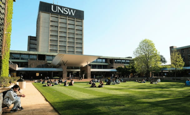 A group of people sitting on top of a lush green field at UNSW University of New South Wales Sydney Main Library
