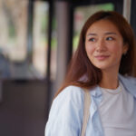A young Asian woman looks out the window, taking in the sights during a bus ride through Sydney.