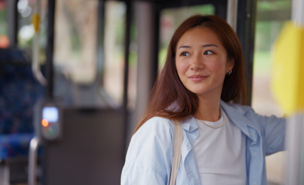 A young Asian woman looks out the window, taking in the sights during a bus ride through Sydney.