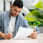Latino man going through paperwork and filling in a form for his international student arrival.
