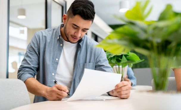 Latino man going through paperwork and filling in a form for his international student arrival.