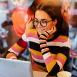 Through Glass View of Two Young Woman Looking at Laptop in a Cafe or Restaurant