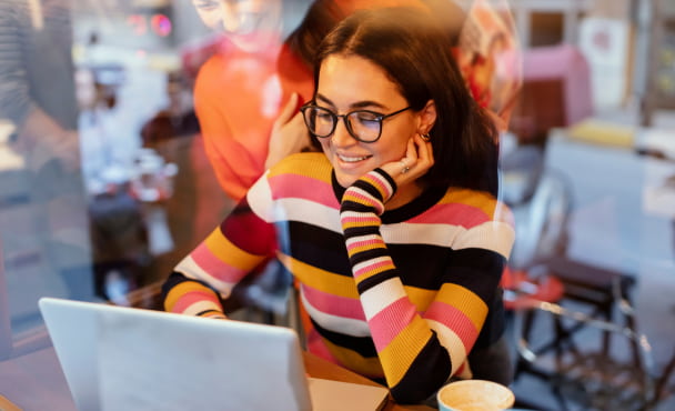 Through Glass View of Two Young Woman Looking at Laptop in a Cafe or Restaurant