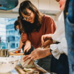 Group of friends preparing dinner in a shared student apartment together in the kitchen