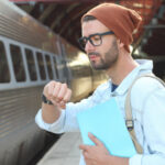 Male student checking the time at train station.
