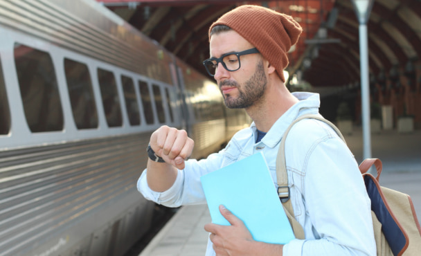 Male student checking the time at train station.