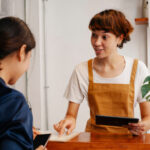 A barista helping a customer with a tablet in a modern café setting. Natural interaction.
